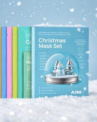 AIMX Christmas Mask Set displayed in snow, with colourful bio-cellulose mask sachets behind the blue gift box.