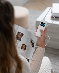 Woman holding the Lerelle Beauty LED mask remote control while relaxing at home.
