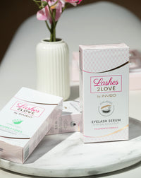Lerelle Beauty Lashes2Love Lash Growth Serum and Biopeptides Serum boxes styled together on marble with flowers