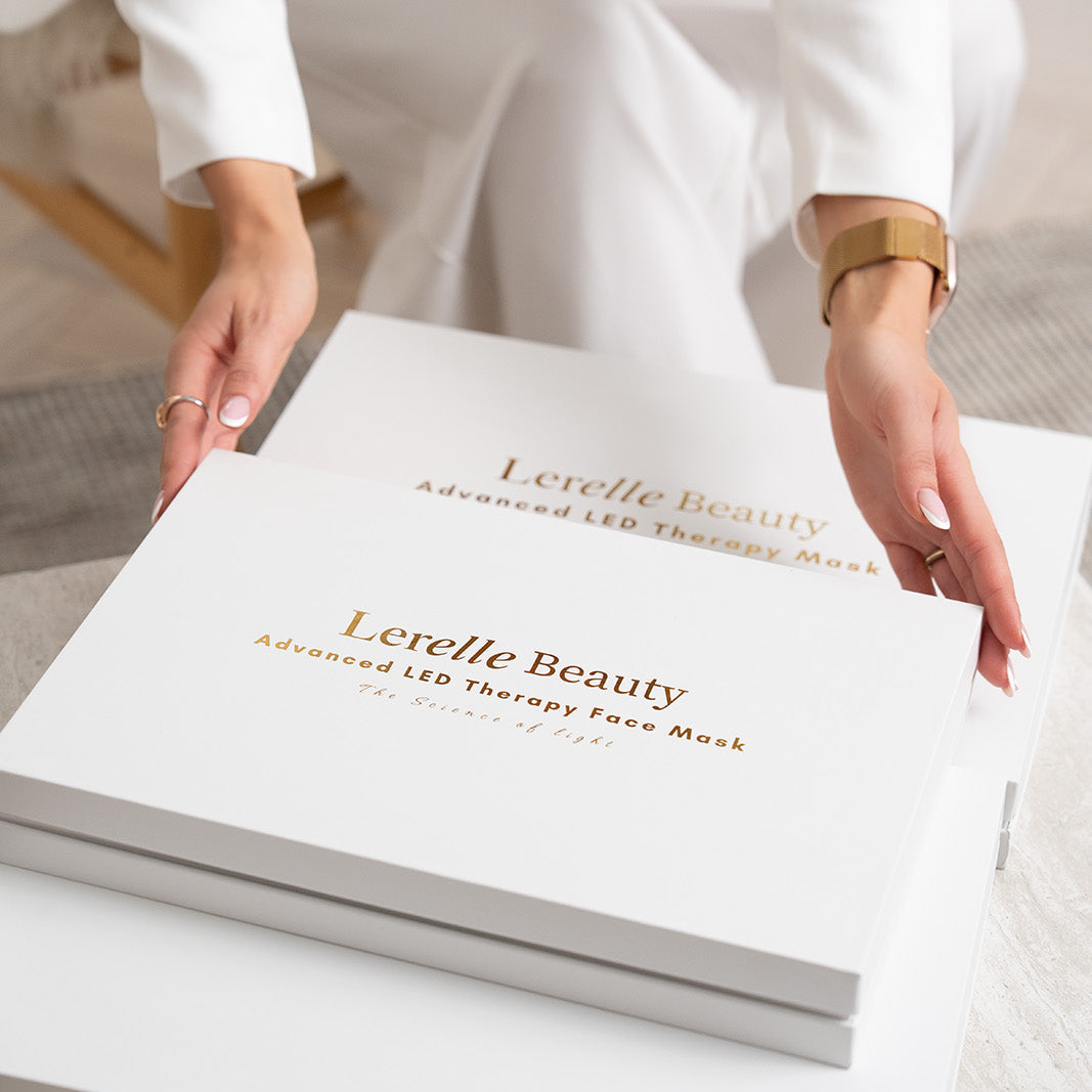 Woman placing the Lerelle Beauty red light therapy face mask gift box on a table, two boxes stacked together